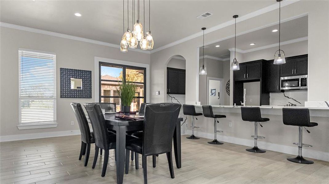 Dining room featuring crown molding, light wood-style floors, recessed lighting, arched walkways, and a chandelier