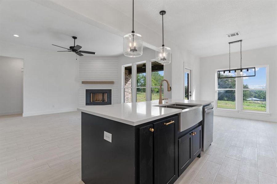 Kitchen with light countertops, decorative backsplash, custom range hood, an island with sink, and recessed lighting