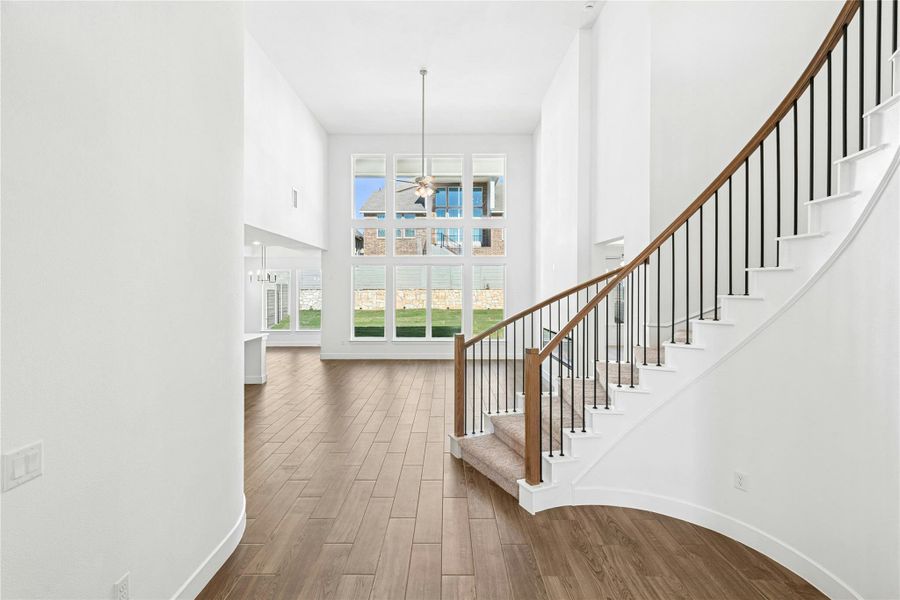 Stairs featuring wood finished floors, a towering ceiling, and a ceiling fan