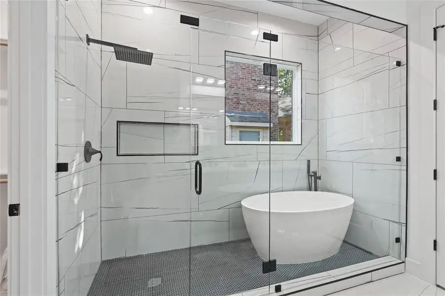 Bathroom with a freestanding tub, a stall shower, and tile walls