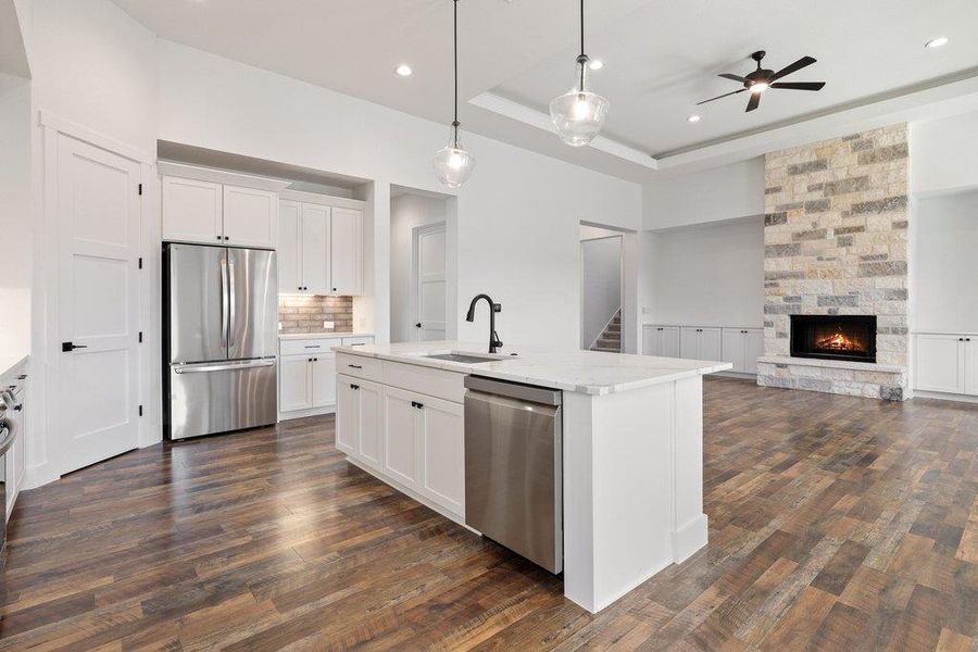 Kitchen with stainless steel appliances, open floor plan, white cabinetry, a kitchen island with sink, and decorative light fixtures