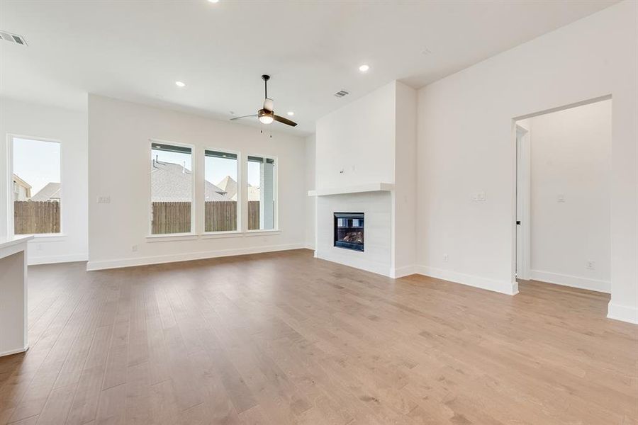 Unfurnished living room featuring a glass covered fireplace, light wood-style floors, recessed lighting, and ceiling fan Unfurnished living room featuring a glass covered fireplace, light wood-style floors, recessed lighting, and ceiling fan