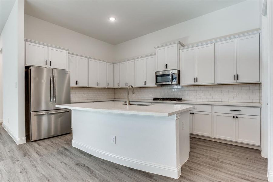 Kitchen featuring white subway tile backsplash, stainless steel appliances, sink, and white cabinets, canned lighting and quartz countertops