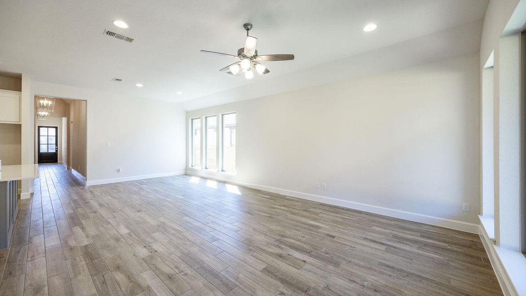 Empty room with recessed lighting, light wood-style floors, ceiling fan, and a chandelier Empty room with recessed lighting, light wood-style floors, ceiling fan, and a chandelier