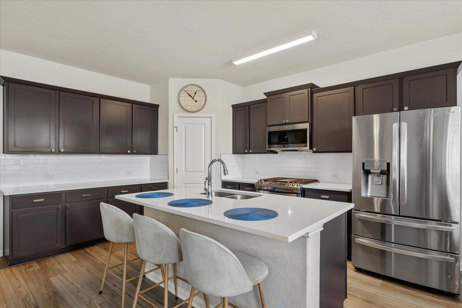 Dark cabinetry and quartz countertops frame a modern culinary space centered around a spacious island.