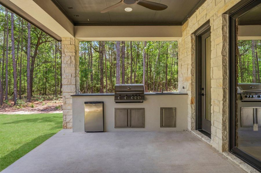 Well-appointed OUTDOOR kitchen showcasing a STAINLESS STEEL grill framed by timeless AUSTIN STONE, designed for seamless outdoor living and ENTERTAINING!