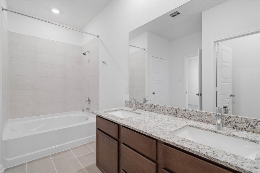 This beautifully updated primary bathroom is move-in ready! It showcases stained cabinetry paired with granite countertops, dual sinks, a large mirror, a spacious tub/shower combination with tile surround, high ceilings, custom paint, and stylish modern finishes throughout. This beautifully updated primary bathroom is move-in ready! It showcases stained cabinetry paired with granite countertops, dual sinks, a large mirror, a spacious tub/shower combination with tile surround, high ceilings, custom paint, and stylish modern finishes throughout.