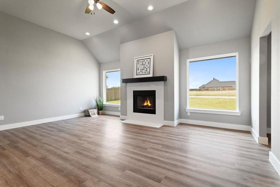 living room with LVP, vaulted ceiling, ceiling fan, and a healthy amount of sunlight