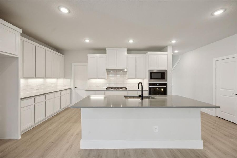 Kitchen with a kitchen island with sink, white cabinetry, sink, and appliances with stainless steel finishes