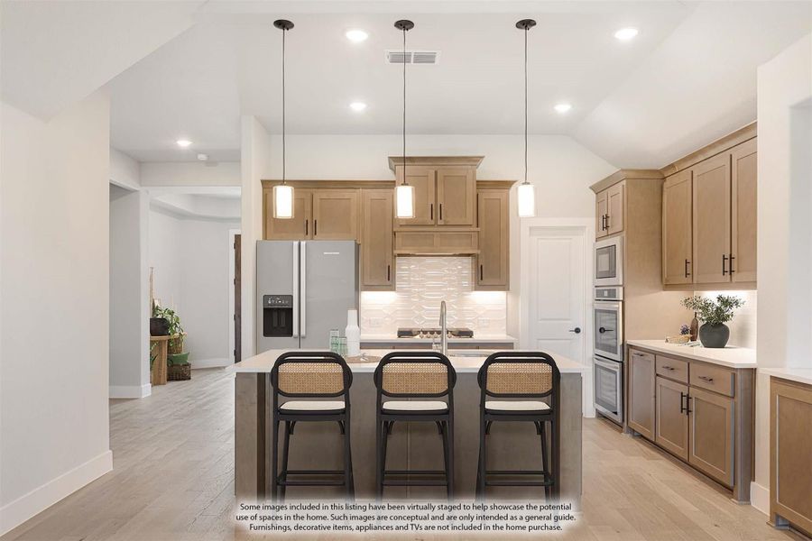 Kitchen with tan wood cabinets, center island with three bar stools, pendant lights, and stainless steel appliances