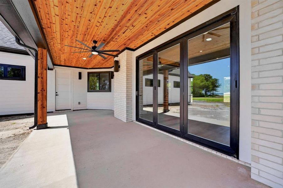 Expansive back porch features a custom cedar ceiling with a sleek ceiling fan and robust wood accents. The accordion door connects the exterior to the homes main living area. Expansive back porch features a custom cedar ceiling with a sleek ceiling fan and robust wood accents. The accordion door connects the exterior to the homes main living area.