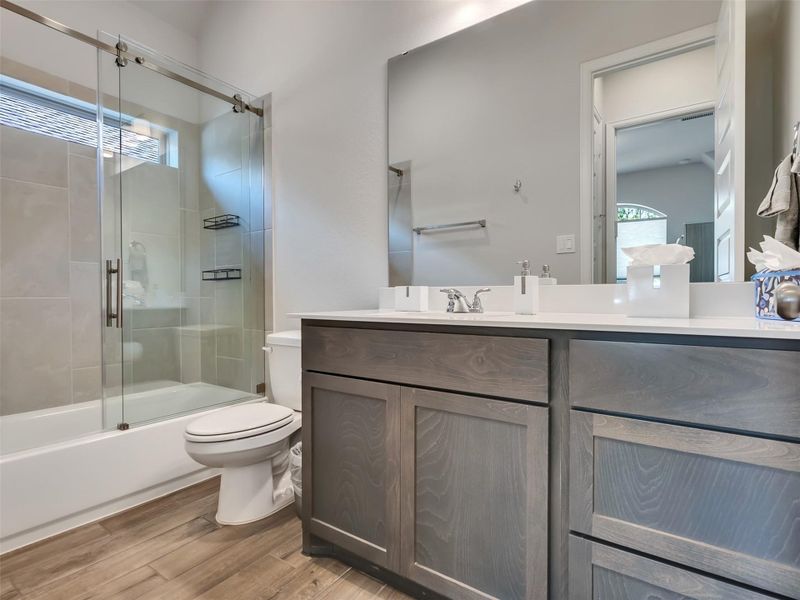 Modern bathroom featuring a sleek glass-enclosed shower, elegant vanity with ample storage, and stylish tile flooring.