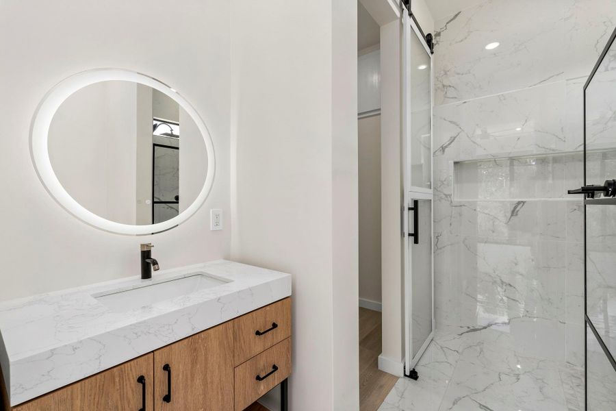 Bathroom with vanity and a marble finish shower