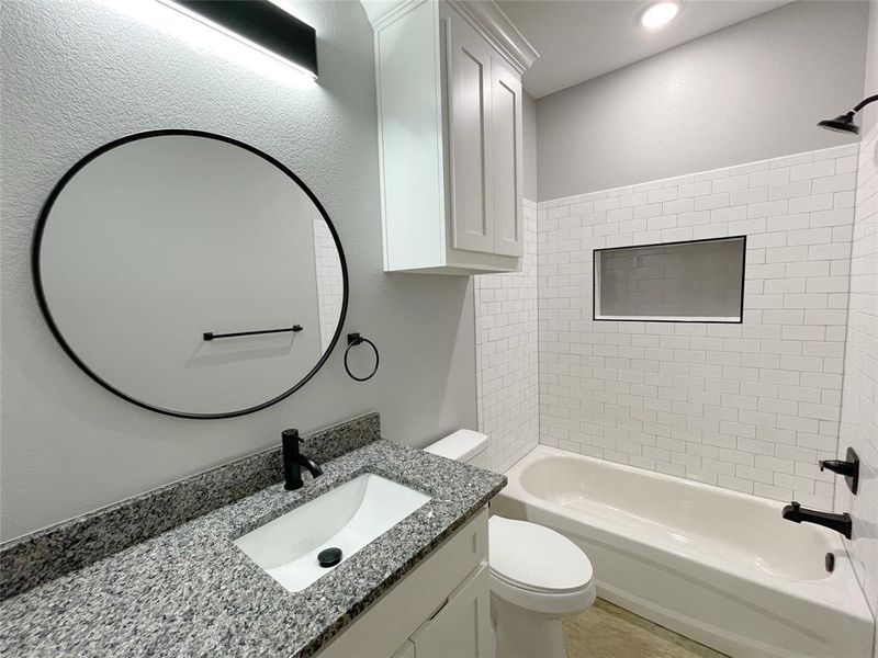 Full bathroom with tiled shower / bath, vanity, and toilet