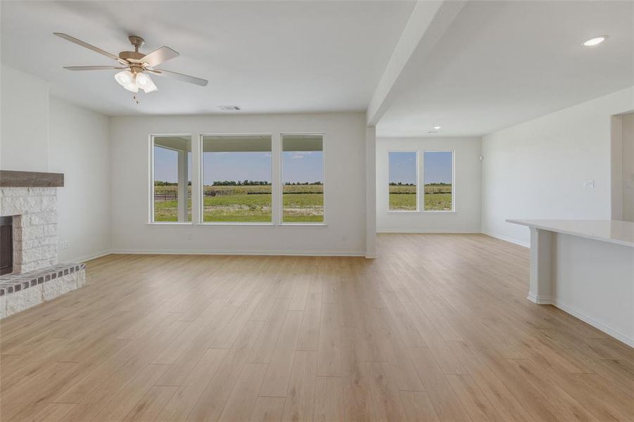 Spacious interior featuring wood-finish flooring, a stone fireplace with a wood mantle, and multiple large windows Spacious interior featuring wood-finish flooring, a stone fireplace with a wood mantle, and multiple large windows