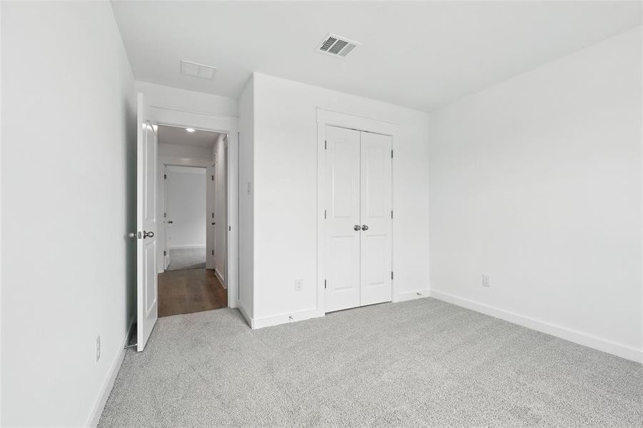Unfurnished bedroom featuring light carpet and a closet