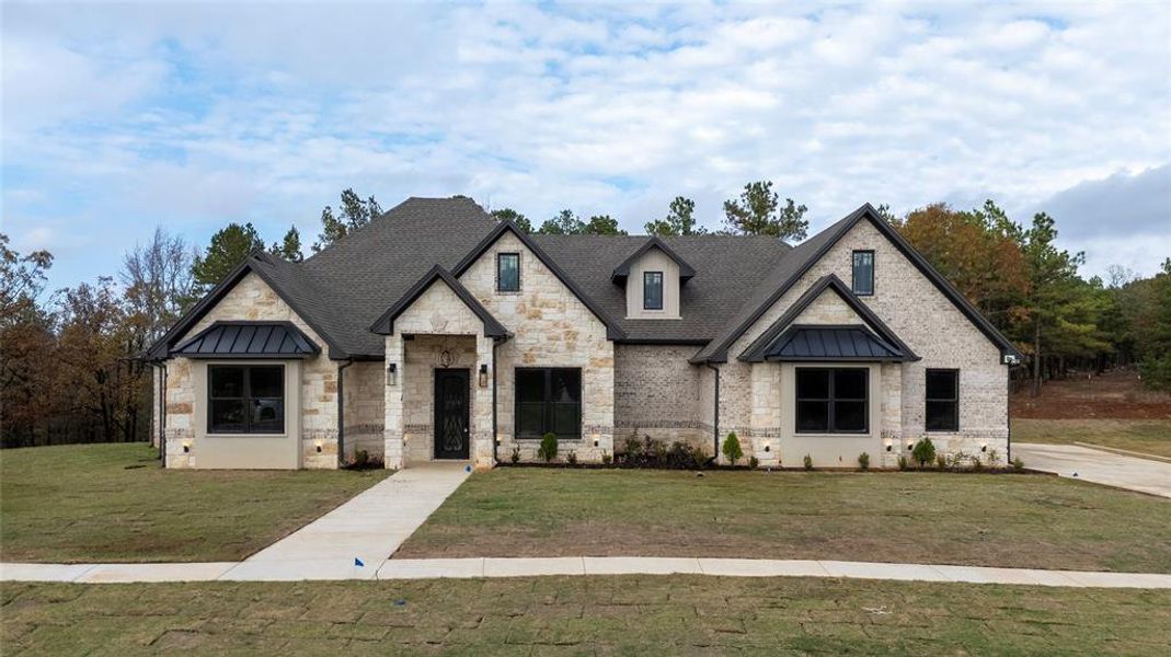 French country style house featuring a standing seam roof, stone siding, and a metal roof
