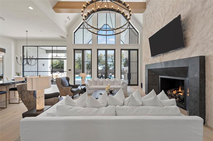 Living area with a chandelier, a premium fireplace, light wood finished floors, recessed lighting, and high vaulted ceiling