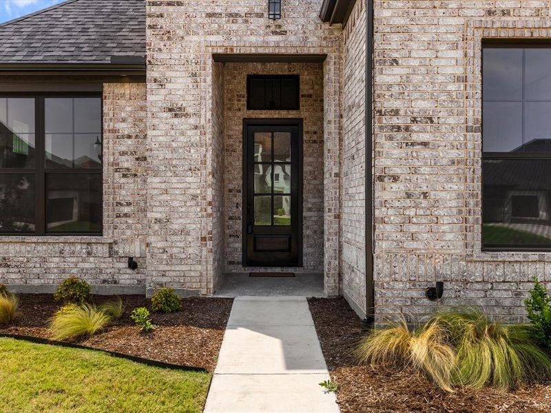 Property entrance with brick siding and a shingled roof Property entrance with brick siding and a shingled roof