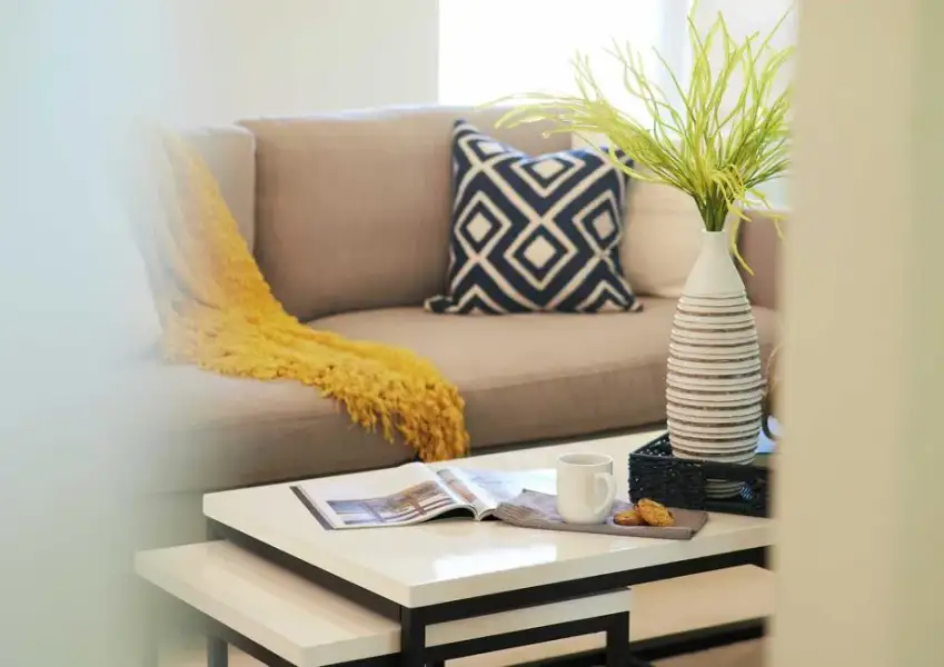 Staged home with sofa and navy pillow, yellow throw, coffee table and vase. Staged home with sofa and navy pillow, yellow throw, coffee table and vase.