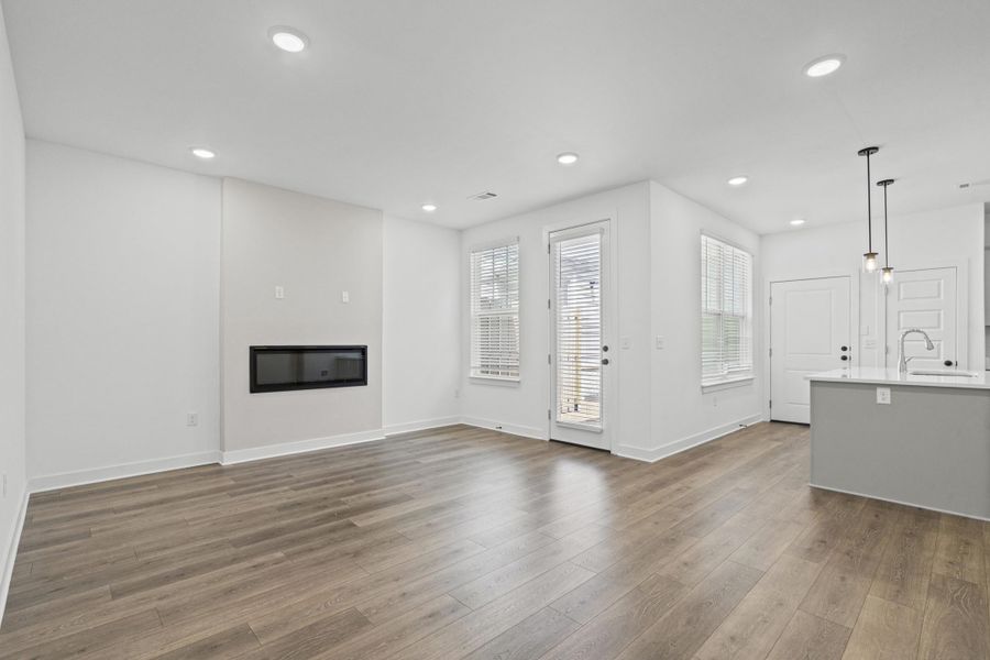 Open-concept living area featuring wood-finish flooring, recessed lighting, and a modern linear fireplace