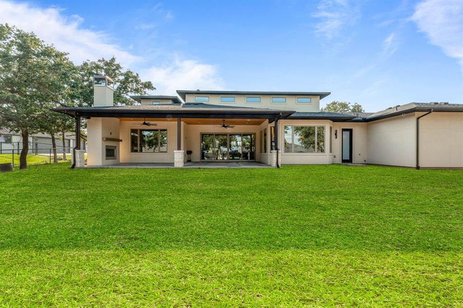 Rear view of property featuring ceiling fan, a patio area, and a lawn