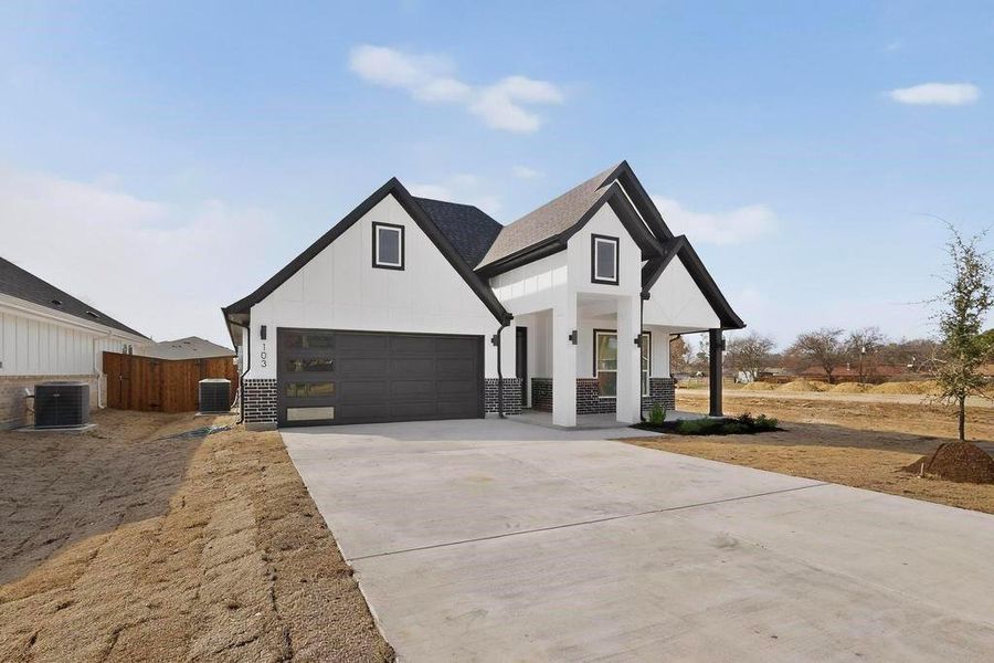 Modern inspired farmhouse with concrete driveway, a garage, a porch, and board and batten siding