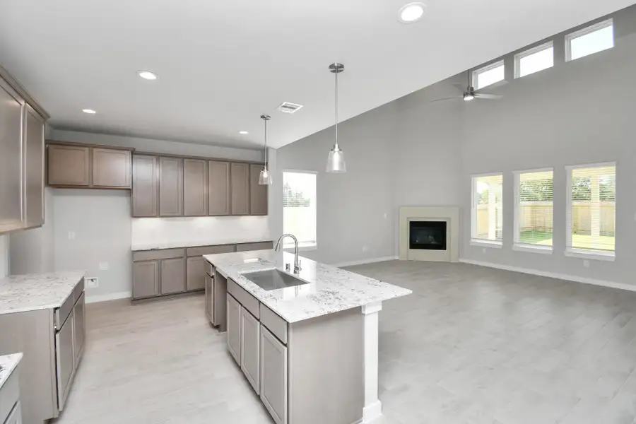 This kitchen is truly a chef's dream! This haven Boasts high ceilings, recessed & pendant lighting, stained wood cabinets, granite countertops, stainless steel appliances, a modern tile backsplash.  All of this overlooks your expansive family room, creating a perfect space for culinary delights and family gatherings. Sample photo of completed home with similar floor plan. Actual colors and selections may vary.