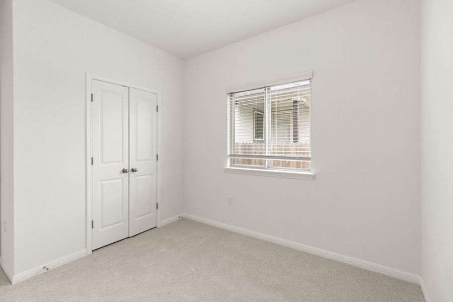 This room features light-colored carpeting, a window with blinds, and white bi-fold doors