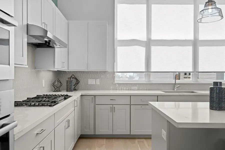 Crisp white cabinetry paired with sleek stone countertops defines this modern culinary space. Crisp white cabinetry paired with sleek stone countertops defines this modern culinary space.