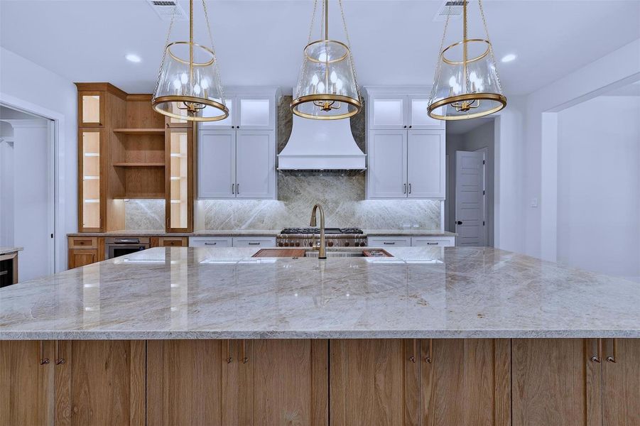 A chef’s kitchen featuring taj mahal countertops and custom cabinetry!