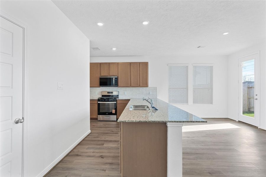 As you enter the Great Room, you are greeted by this spacious kitchen with a long granite countertop in Caramel Cream and added breakfast bar.