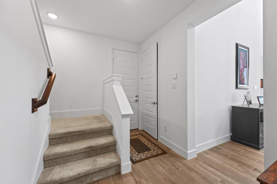 This photo shows the convenient entry from the garage, which is tucked away from the main living area. It features a staircase leading to the second floor and offers a glimpse of the dedicated mudroom area and half bath.
