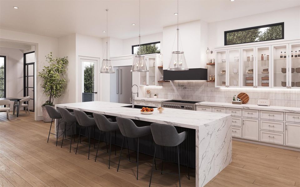 This stunning chef's kitchen showcases a dramatic Quartz waterfall island with ample seating, perfect for entertaining.  Crisp white inset cabinetry and glass front storage maintain visual lightness, while black accents and Polished Nickel pendant lighting introduce depth and structure.  Stainless Appliances, custom hood, Pot Filler, under-cabinet lighting, warm wood floors, and abundant natural light complete this elegant, modern space.