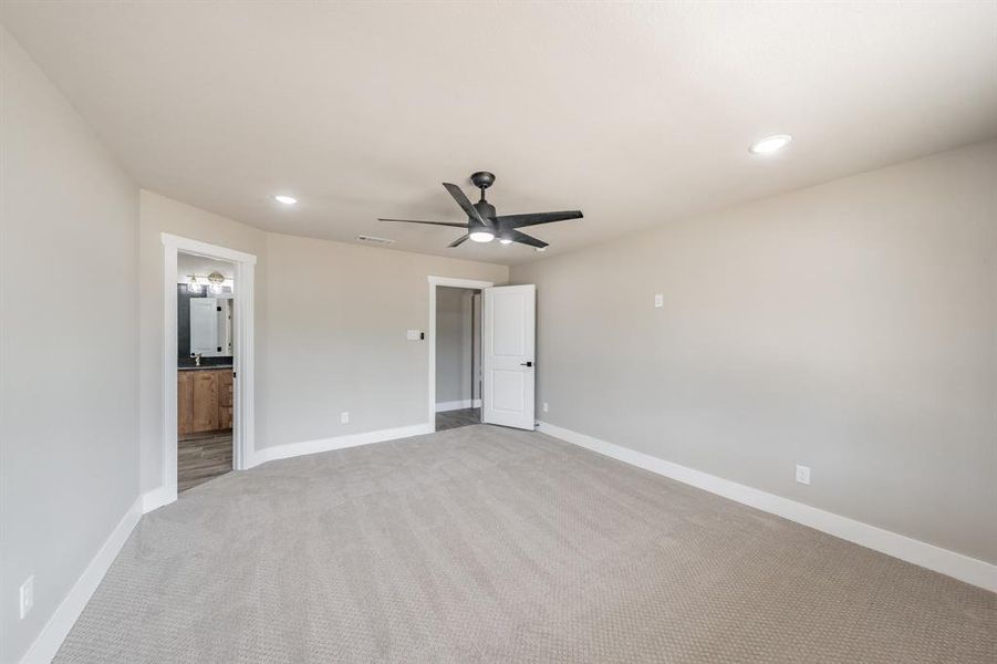 Unfurnished bedroom with recessed lighting, carpet floors, a ceiling fan, and ensuite bath Unfurnished bedroom with recessed lighting, carpet floors, a ceiling fan, and ensuite bath