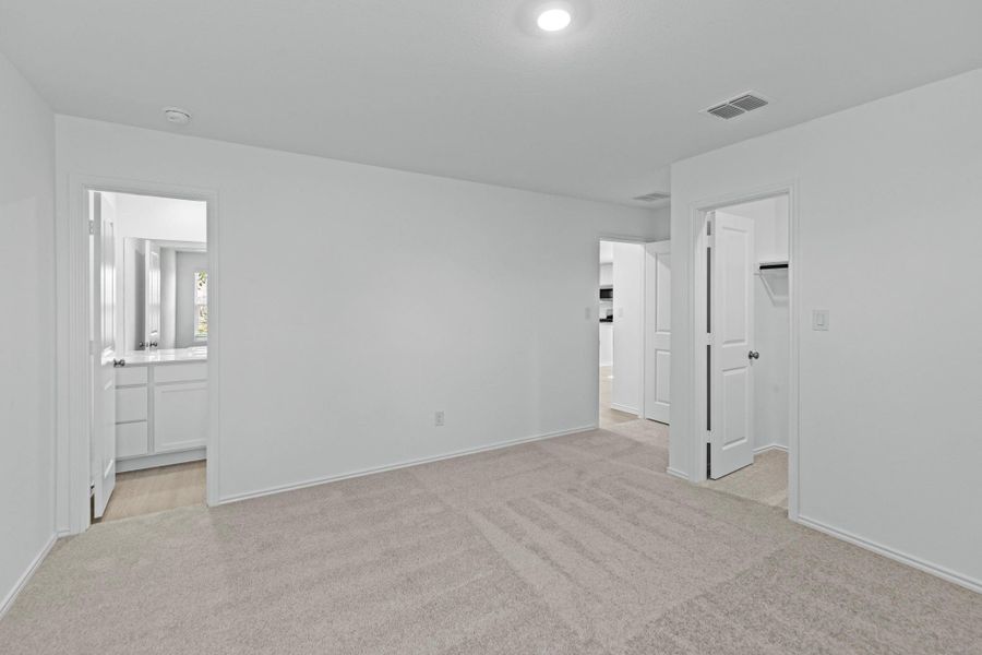 Unfurnished bedroom with light carpet, a spacious closet, and ensuite bathroom Unfurnished bedroom with light carpet, a spacious closet, and ensuite bathroom