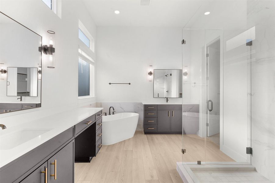 Bathroom with a soaking tub, a shower stall, two vanities, tile walls, and recessed lighting