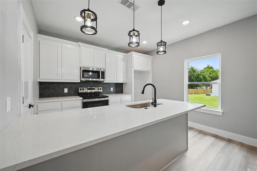 Kitchen with appliances with stainless steel finishes, a sink, backsplash, white cabinetry, and recessed lighting