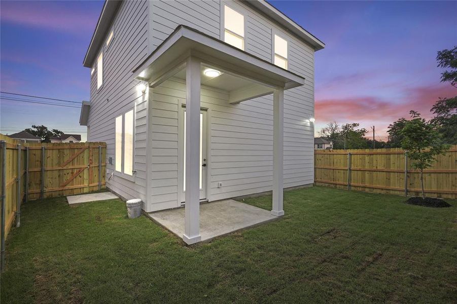 Back of house at dusk featuring a fenced backyard and a patio area