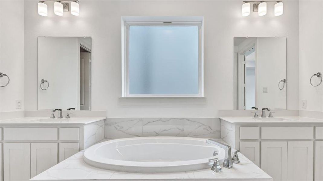 Bathroom with tiled tub and dual bowl vanity