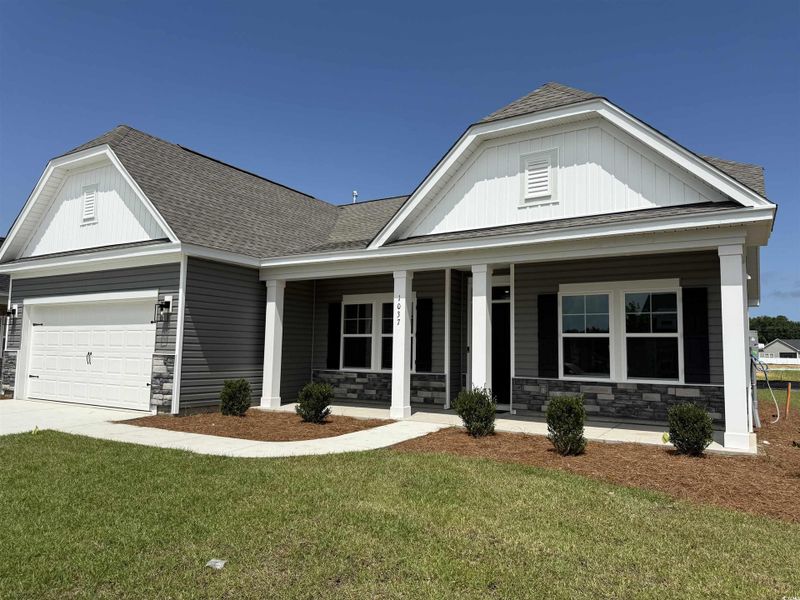 View of front of property with stone siding, a porch, roof with shingles, and a front yard View of front of property with stone siding, a porch, roof with shingles, and a front yard