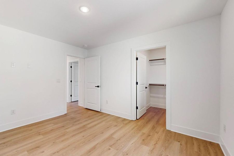 Unfurnished bedroom featuring light wood-style flooring and a walk in closet
