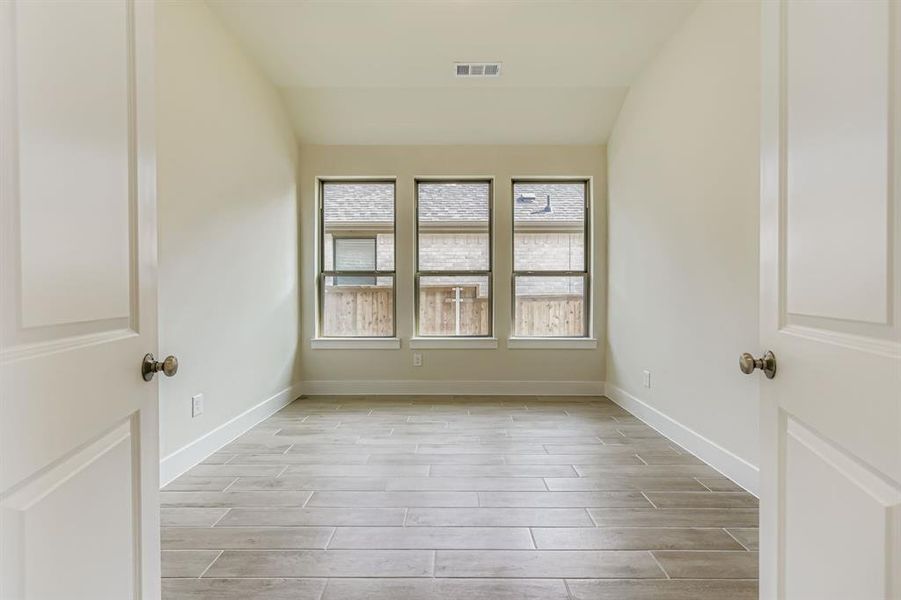 Unfurnished room with wood tiled floors and vaulted ceiling