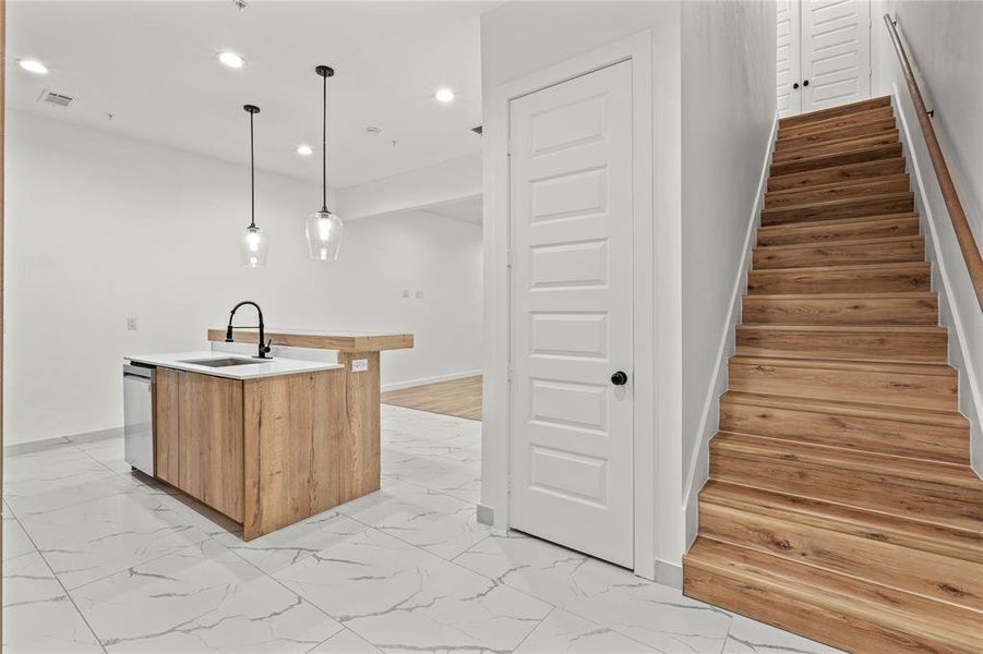 Kitchen featuring light marble finish floors, recessed lighting, a kitchen island with sink, light countertops, and decorative light fixtures Kitchen featuring light marble finish floors, recessed lighting, a kitchen island with sink, light countertops, and decorative light fixtures
