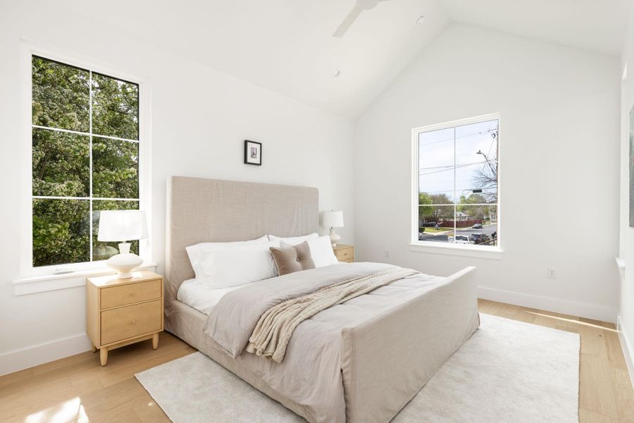 Bedroom featuring light wood-style flooring, ceiling fan, and a high ceiling Bedroom featuring light wood-style flooring, ceiling fan, and a high ceiling