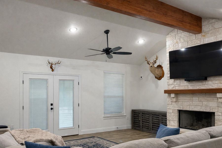 Living room with french doors, a large fireplace, wood finished floors, ceiling fan, and recessed lighting Living room with french doors, a large fireplace, wood finished floors, ceiling fan, and recessed lighting