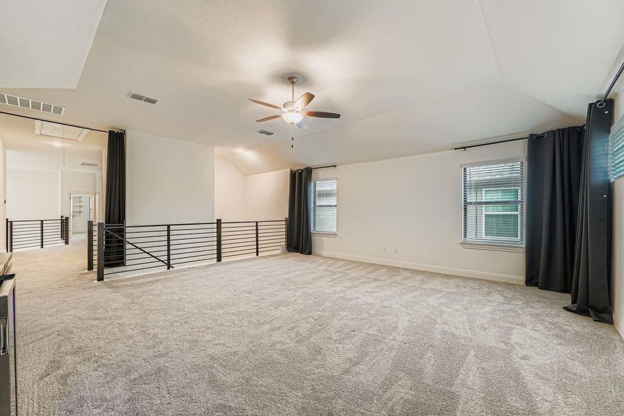 Empty room with attic access, lofted ceiling, light carpet, and a ceiling fan Empty room with attic access, lofted ceiling, light carpet, and a ceiling fan