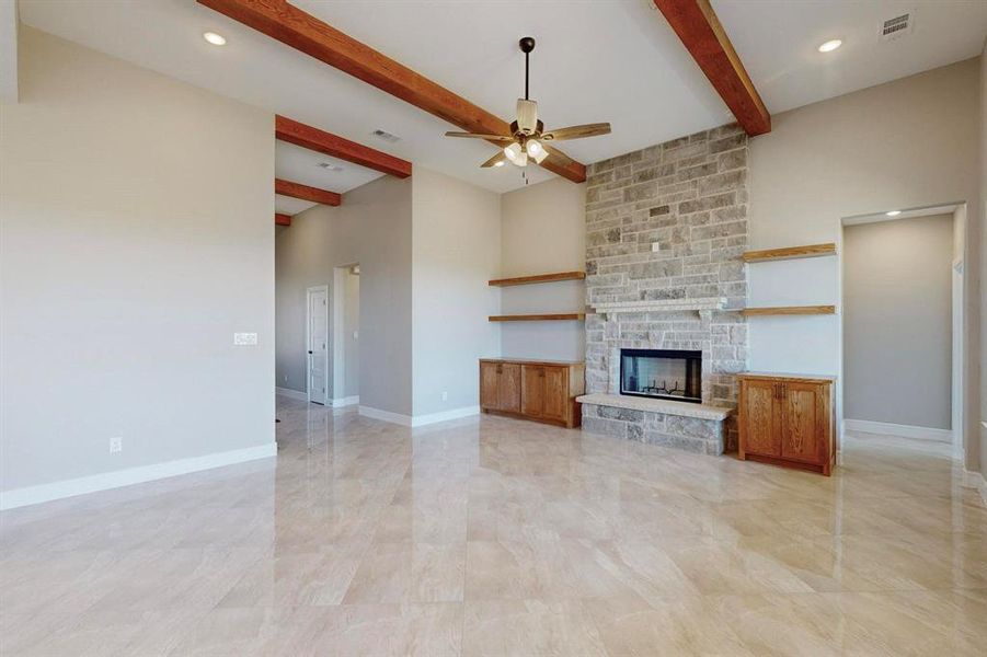 Unfurnished living room with beamed ceiling, light tile patterned flooring, a fireplace, and ceiling fan