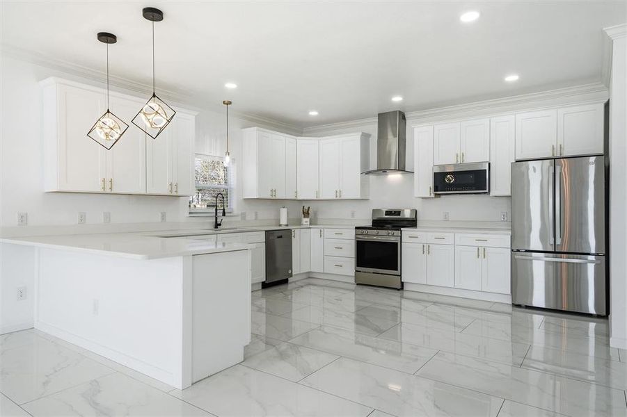 Kitchen with appliances with stainless steel finishes, a peninsula, ornamental molding, white cabinetry, and recessed lighting Kitchen with appliances with stainless steel finishes, a peninsula, ornamental molding, white cabinetry, and recessed lighting