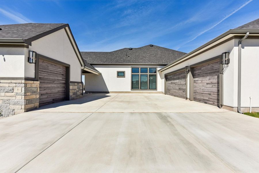 View of home's exterior with a garage, stucco siding, concrete driveway, and roof with shingles